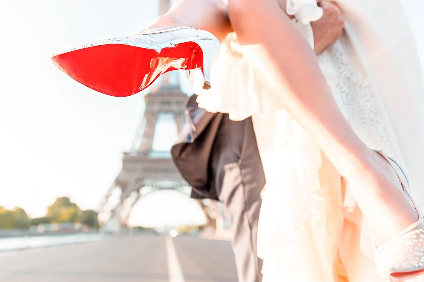 Groom carrying his bride across Pont d'Iéna at sunrise with the Eiffel Tower in the background during a Paris wedding