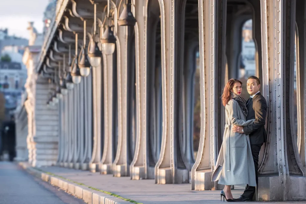 Stylish couple posing against Bir Hakeim Bridge arches in Paris during cinematic photography session