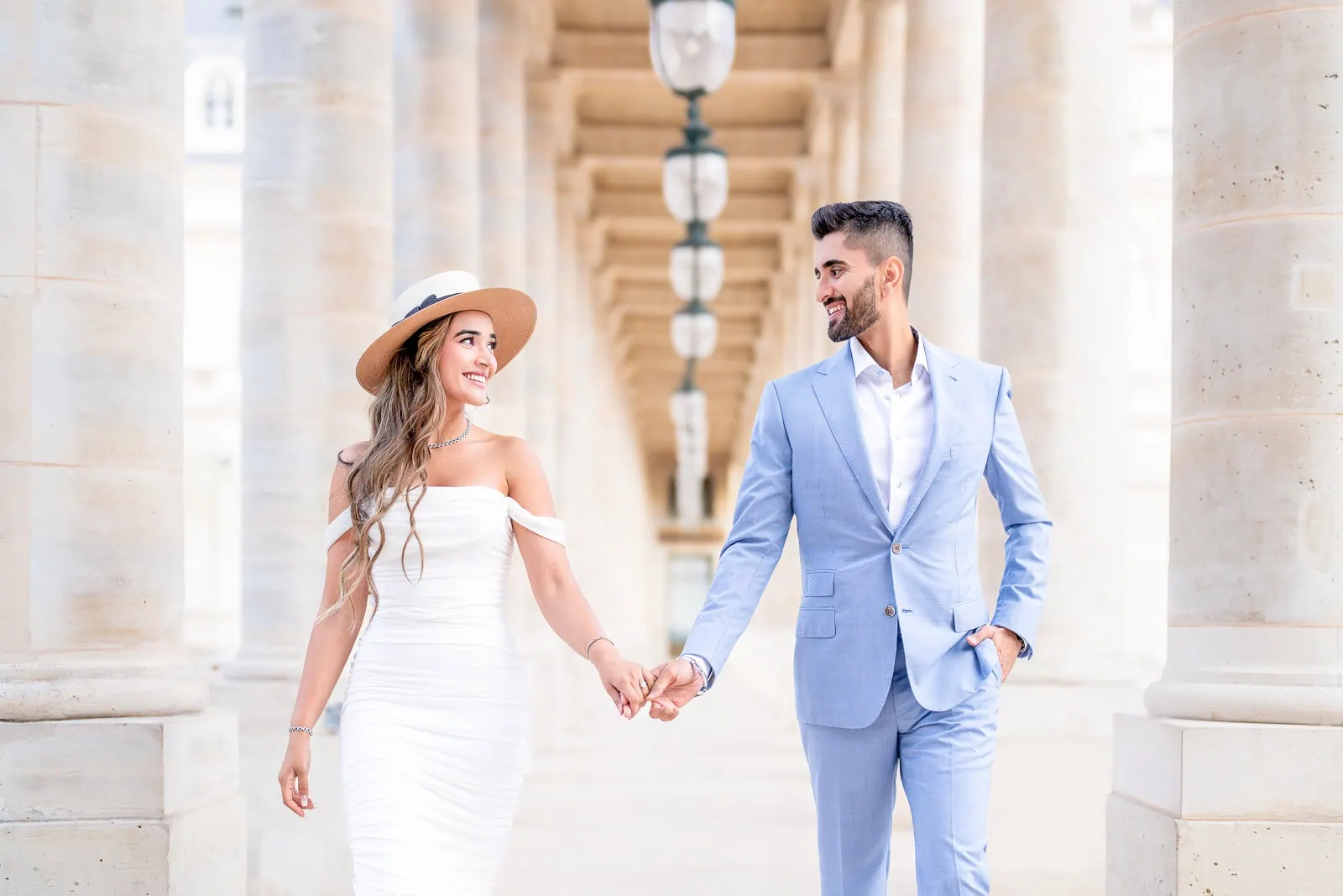 Indian couple in white hat and blue linen holding hands at Palais Royal esplanade, Paris couple photographer session