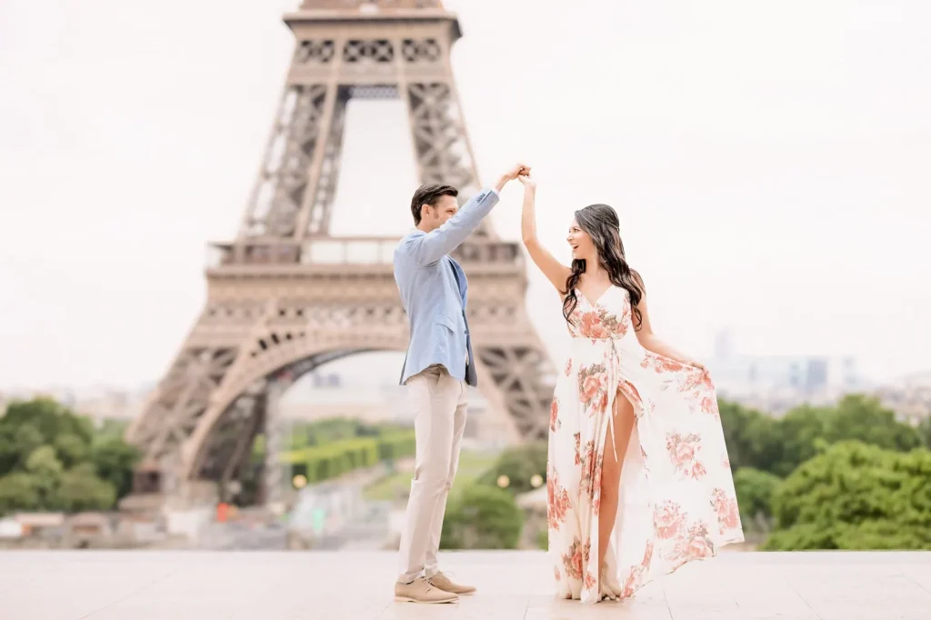 Engaged couple twirling at Trocadéro plaza sunrise with Eiffel Tower backdrop, Paris engagement photographer session
