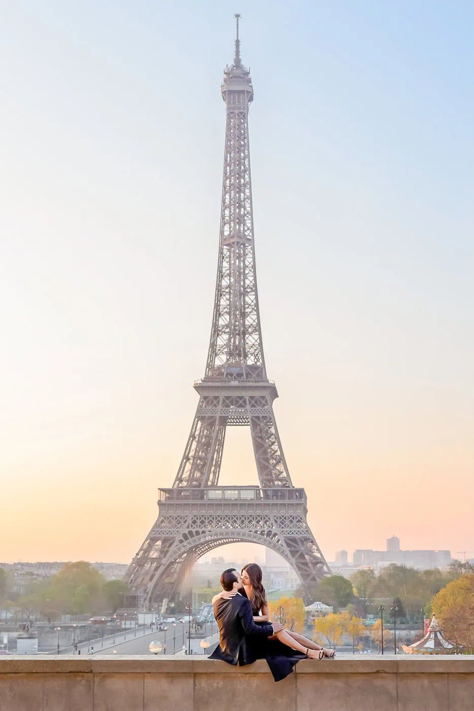 Stylish engaged couple posing on wall at Trocadéro sunrise with Eiffel Tower backdrop, Paris engagement photographer