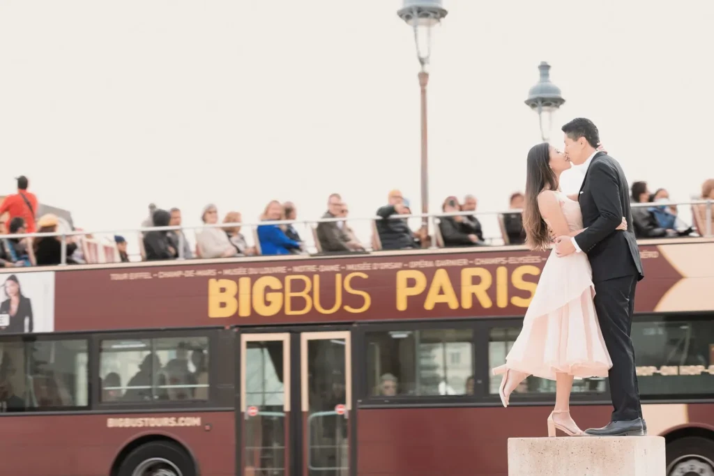 Stylish couple portrait at Louvre with red Big Bus and tourists taking photos, creative Paris photographer session