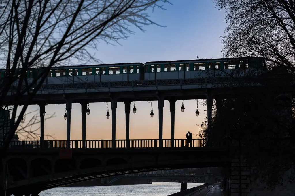 Winter couple silhouette at Bir Hakeim Bridge evening with signature lanterns and pink sky over Passy, unique perspective Paris photographer