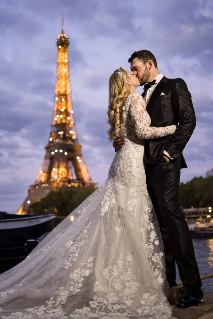 Wedding couple kissing at Seine riverbank during Eiffel Tower sparkling lights at blue hour, Paris wedding photographer