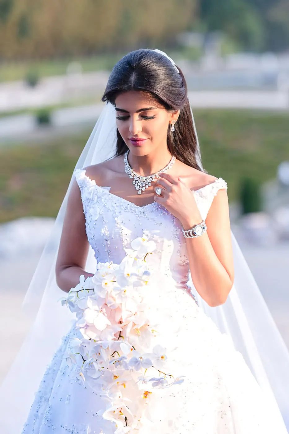 Royal Bride in Dior Couture adjusts her diamond necklace at Vaux le Vicomte Castle, captured by our awarding winning Paris wedding photographer