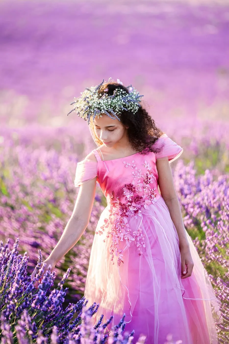 Young girl in purple dress exploring blooming lavender fields in Provence during July family photoshoot